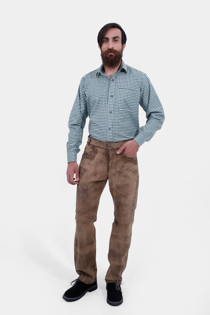 A man with a beard wearing a green checkered shirt and tan Addison Oktoberfest Lederhosen Long. He is standing with a neutral expression, hands by his side, showcasing the full outfit.