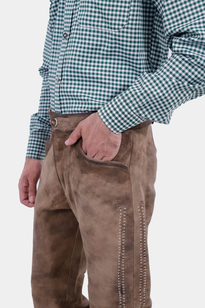 Another angle showing the Addison Oktoberfest Lederhosen Long, focusing on the embroidered pocket and side details, with the man's hand in the pocket.