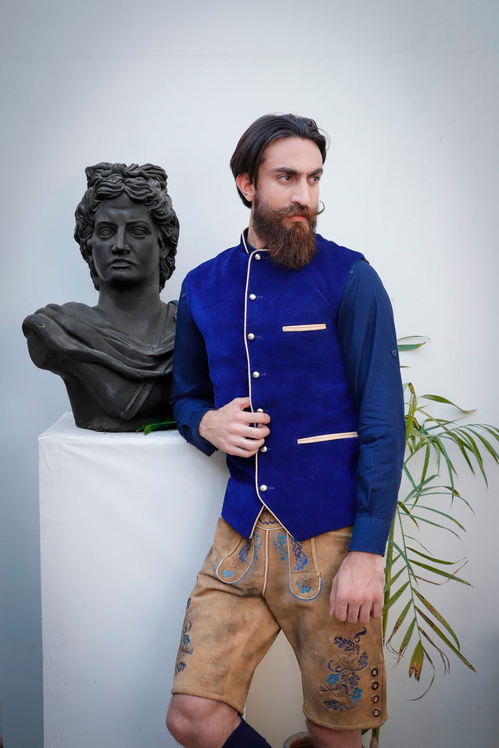 Close-up of a man in a deep blue Bavarian lederhosen vest, showcasing the detailed silver buttons and beige piping.