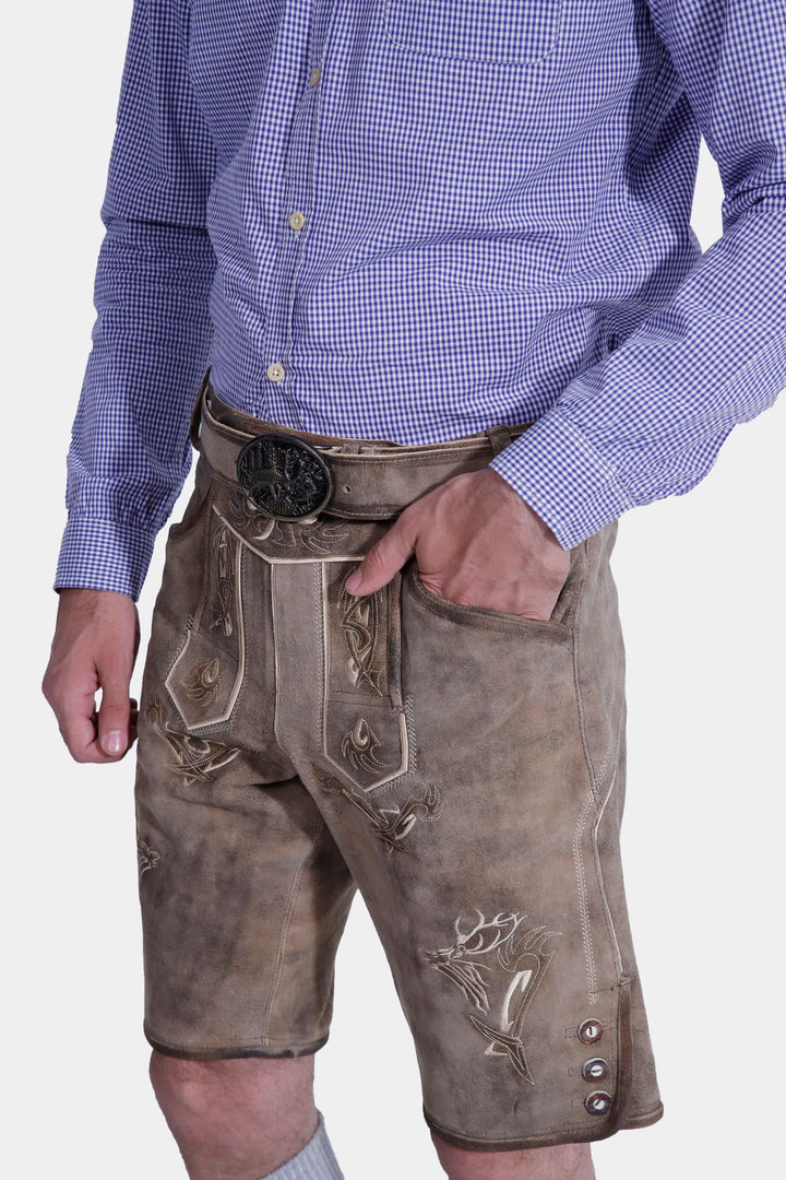 Close-up of Bodensee Lederhosen showcasing detailed embroidery, man's hand in pocket.