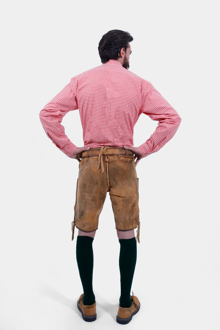 Rear view of a man wearing Chiemsee Lederhosen and a pink checkered shirt, showing the back design and fit of the shorts.