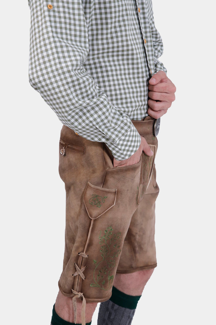 Side view of a man wearing a green and white checkered shirt and brown leather lederhosen, showcasing the side pocket and intricate embroidery on the lederhosen.