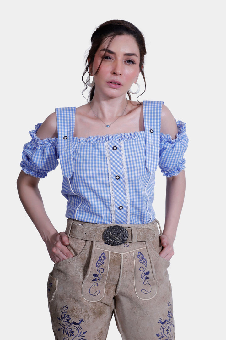 Woman posing with hands on hips in traditional sandy beige Desert Sand Lederhosen, highlighting the intricate embroidery and tailored fit.