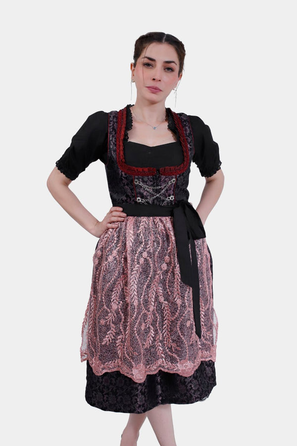 A woman in Dirndl Franka with a detailed black silk bodice, standing with hands on hips against a white background.