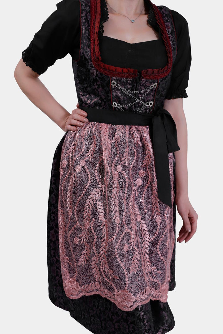 Front side view of a woman wearing a Dirndl Franka, highlighting the tied black bow and lace-trimmed skirt.