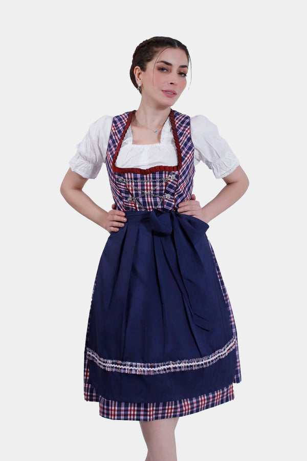 Woman in Dirndl Hilker, hands on hips, showcasing the sapphire bodice with plaid accents and a flowing navy skirt.