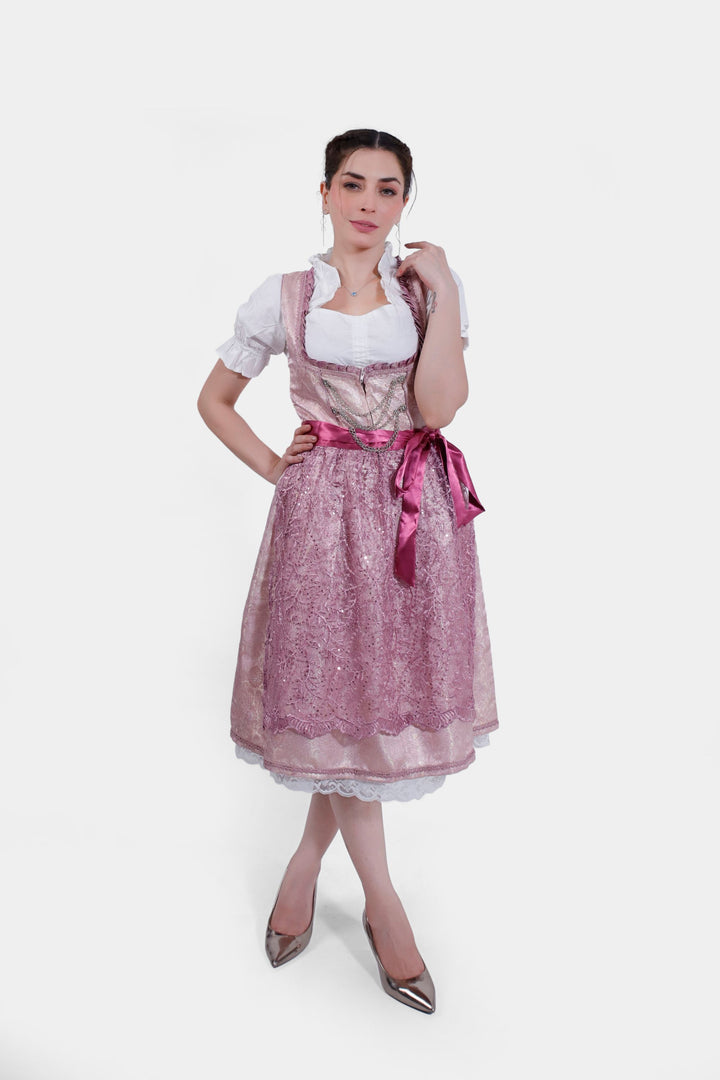 Full-body portrait of a woman in Dirndl Jessica Schwarz with a shimmering rose skirt, white blouse, and intricate bodice detailing, standing straight.