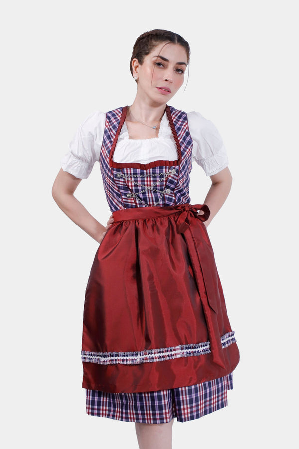 Woman in Dirndl Zsa Inci, posing with hand on hip, showcasing the vibrant crimson bodice and plaid pattern.