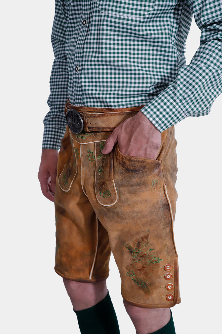 Side view of a man wearing the Durant Lederhosen Outfit, showing the green checkered shirt tucked into brown leather Lederhosen with green embroidery and a side pocket detail.