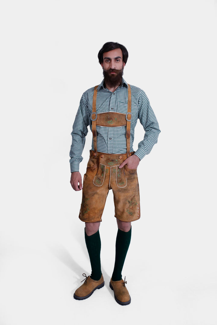 Full-body view of a man wearing the Durant Lederhosen Outfit, featuring a green checkered shirt, brown leather Lederhosen with green embroidery, green knee-high socks, and brown shoes.