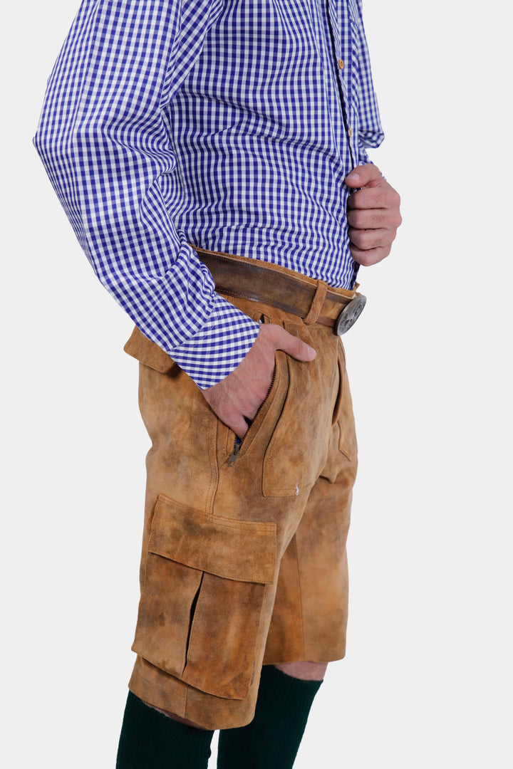 A close-up view of the Franzl Lang Cargo Lederhosen in Tuscan Sunburst, showing the detailed leather texture and side pocket, worn with a blue and white checkered shirt.