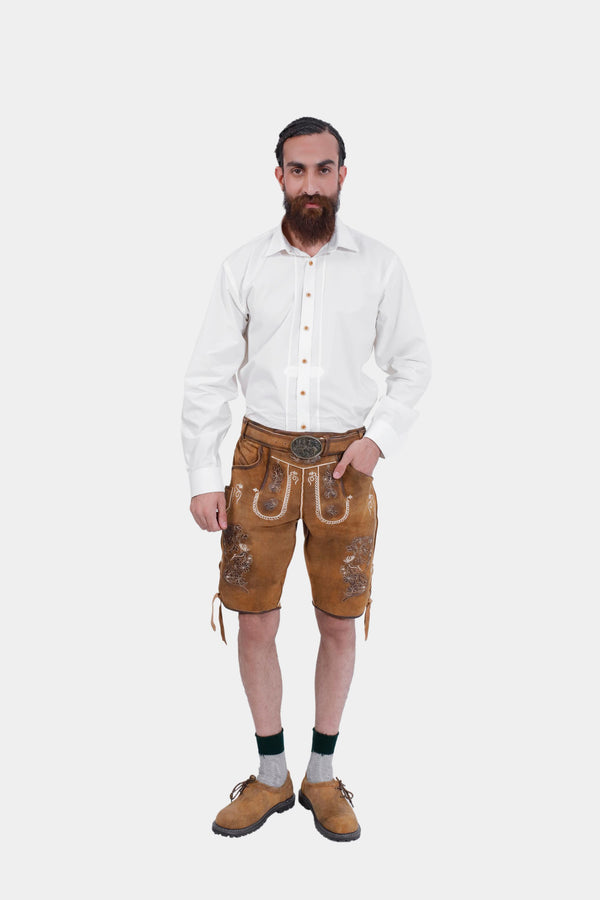 Front view of a  man in traditional Freud Lederhosen with Traditional ornate embroidery and a white shirt, posing with hands on hips.