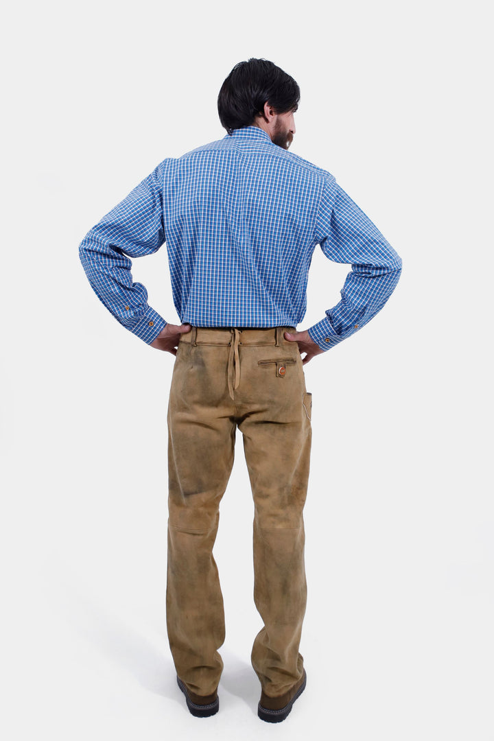 A back view of the man wearing the Goretzka lederhosen and blue checkered shirt. His hands are on his hips, displaying the back details of the lederhosen.