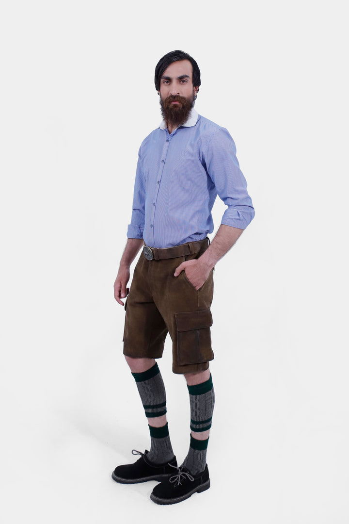 Three-quarter view of a man in Hallstatt Cargo Lederhosen, hands in pockets, paired with knee-high socks and black shoes, showcasing traditional Bavarian fashion.