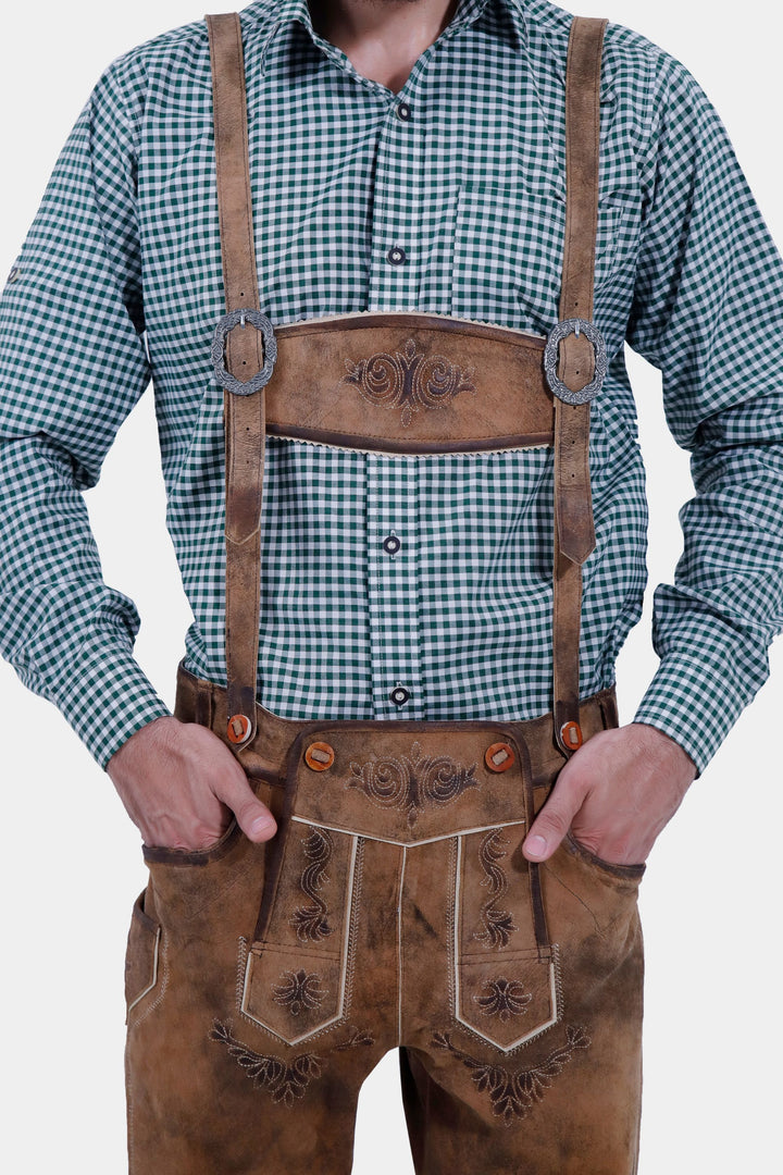 Close-up of a man in a green checkered shirt and Hesse Bundhosen with suspenders. The brown leather pants feature detailed floral embroidery and high-quality leather material, showcasing the traditional Bavarian style.