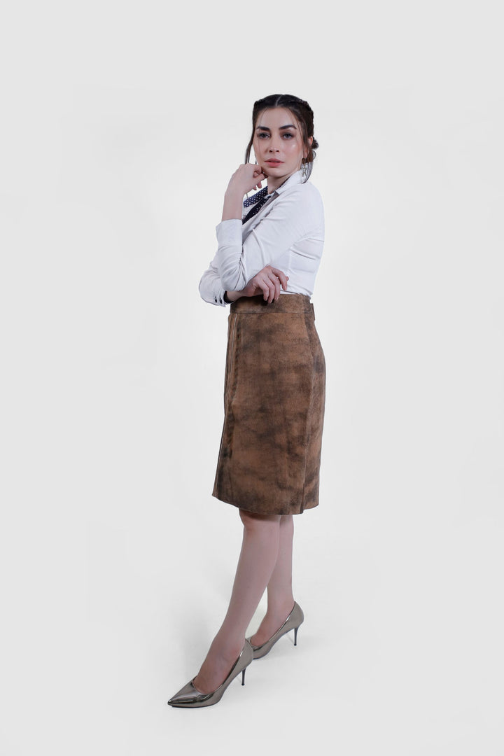 Woman in the IRINA Lederhosen Skirt in brown leather and white button-up shirt, standing with her hand on her hip, showing the skirt's front and side profiles.