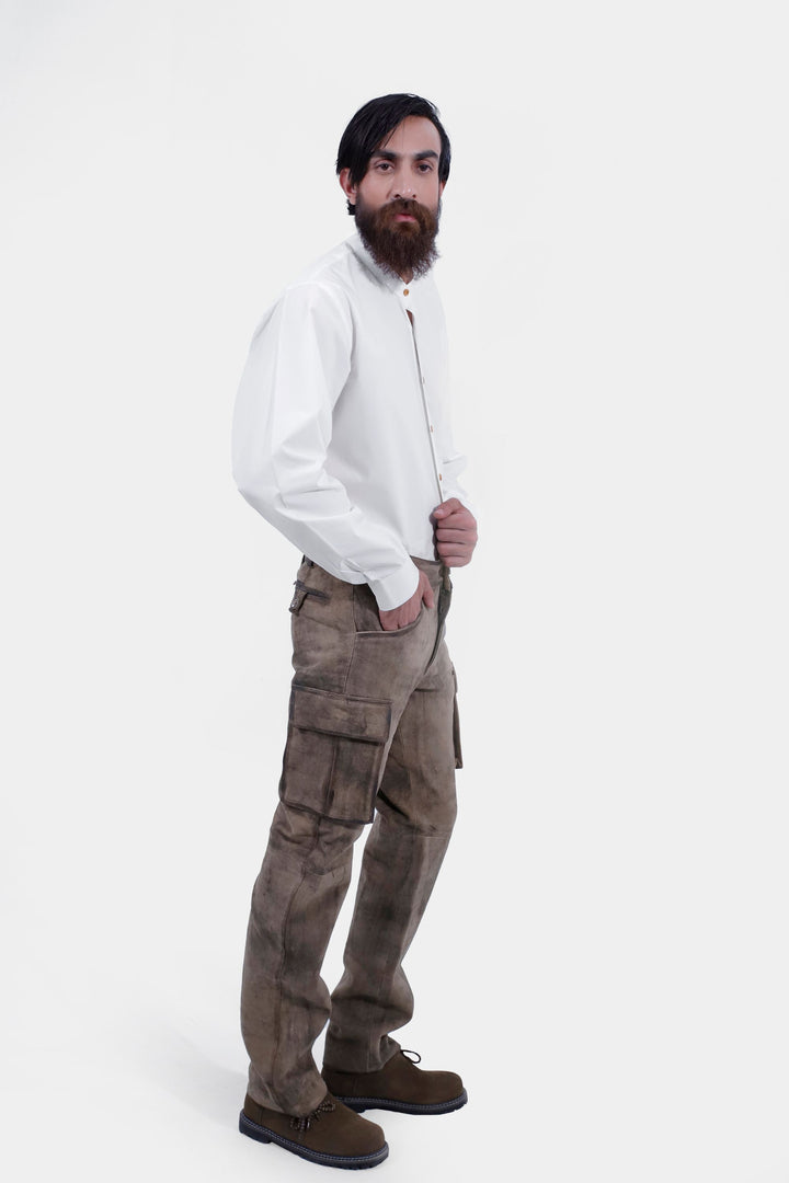 Full-body shot of a person standing and facing the camera, dressed in Königssee Cargo Lederhosen Long Pant and a white button-up shirt.