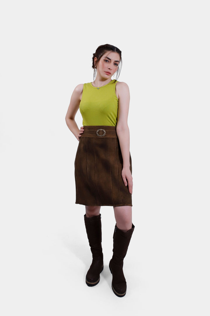 Full body view of a woman wearing the Leni Lederhosen Skirt in Rustic Oak, paired with a green top and brown boots. lederrock echtleder, oktoberfest lederrock