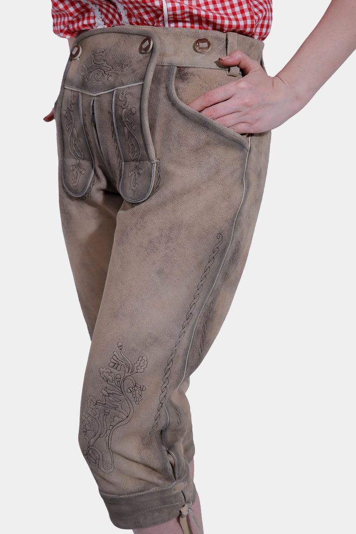 Another side view of the woman in brown leather lederhosen, showcasing the pocket and side embroidery of the pants.