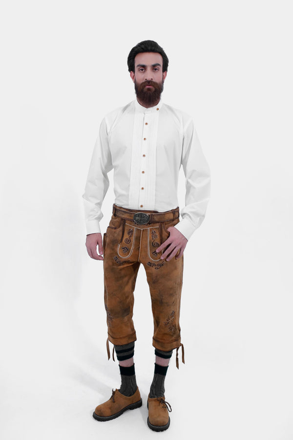 A man standing and wearing Lothar Bundhosen Outfit with detailed embroidery. With white traditional shirt and along with brown shoes and tan brown socks. lederhose tracht damen , tracht oktoberfest 