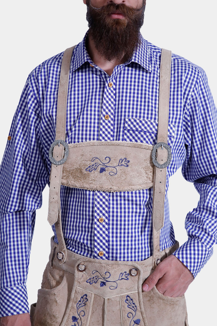 Front view of a man in a Mookie Lederhosen Outfit, showing the blue and white checkered shirt, tan leather lederhosen with blue embroidery, and decorative suspenders.