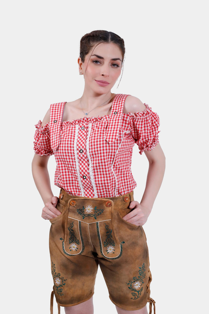 Close-up of a woman in Munich Majesty lederhosen, focusing on the bib embroidery and front pocket details.