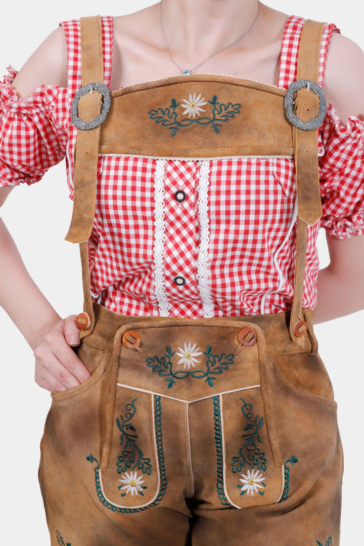 Woman wearing Munich Majeesty lederhosen in Brownish Gold, showcasing the detailed natural color embroidery on the bib and legs, paired with a white button-up shirt.