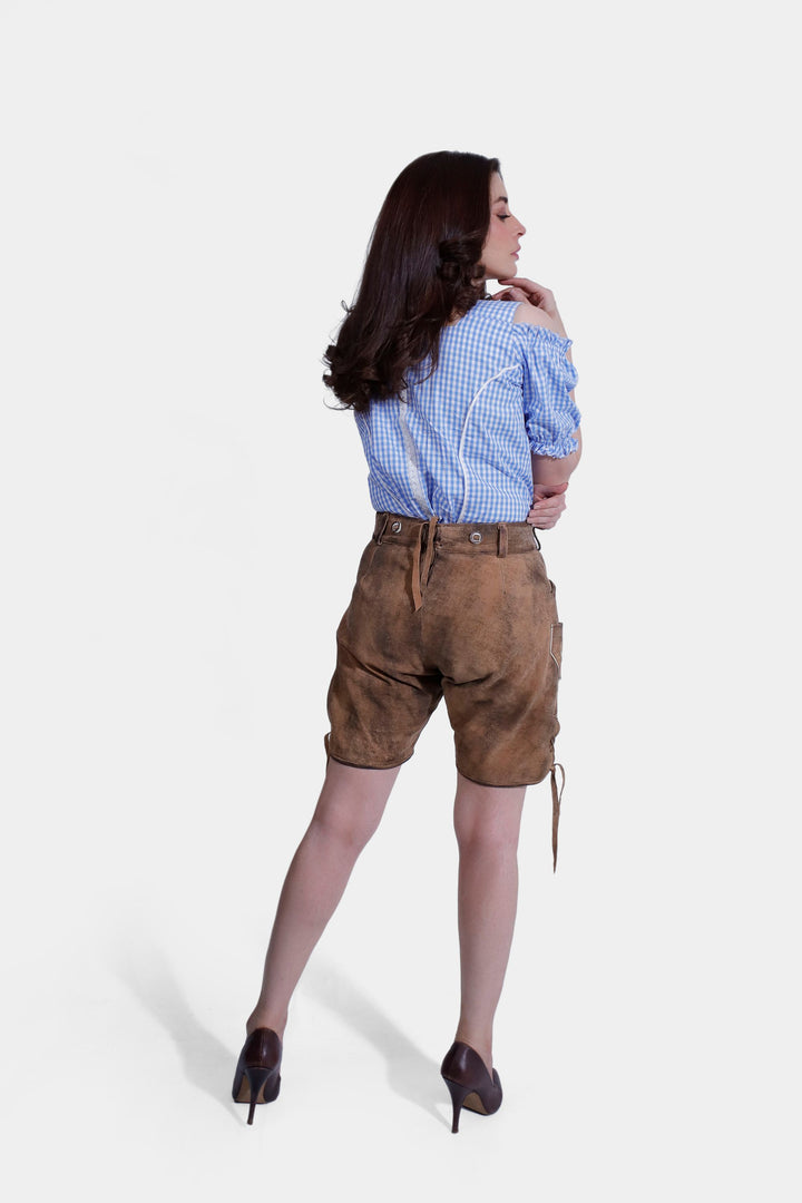 "Full-length back view of a woman in a blue and white checkered Bavarian shirt and light brown lederhosen with embroidery, standing with a relaxed pose.