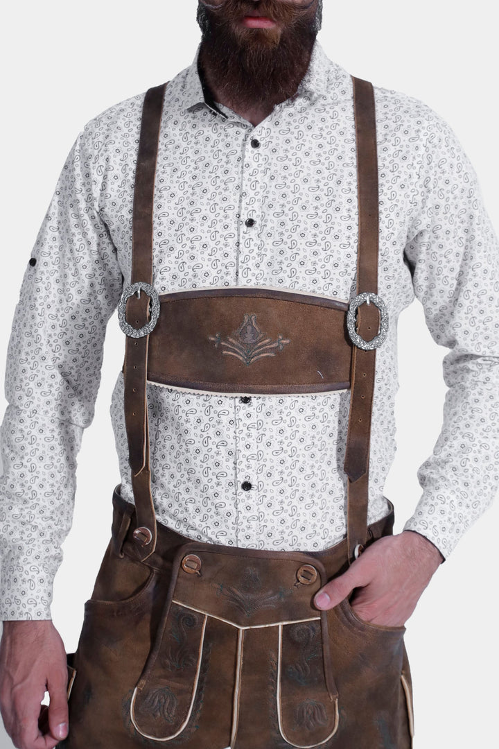 Close-up of the embroidery and button details on brown leather lederhosen, highlighting the craftsmanship against a white background.