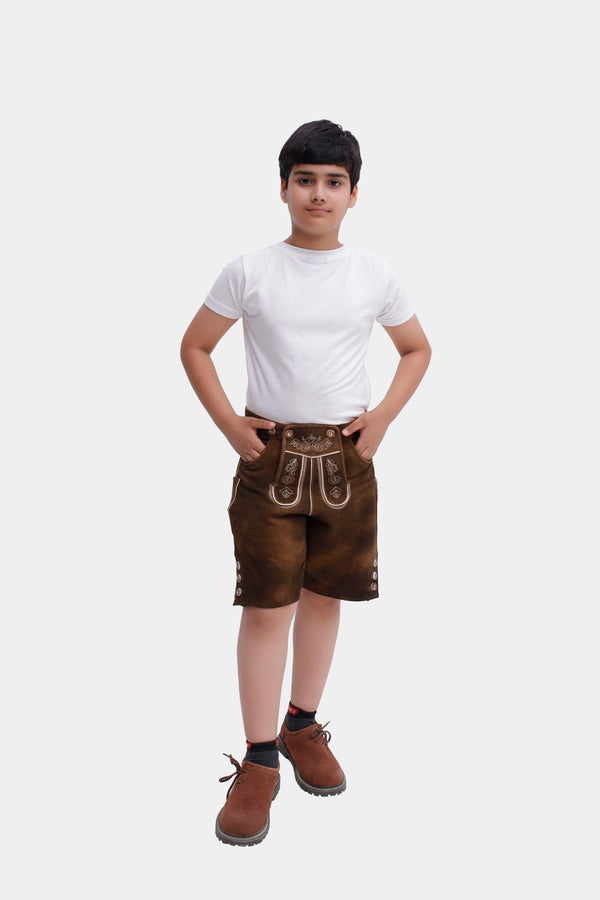 Full-body front view of a boy in Sebastian Lederhosen in Cocoa Rust, paired with a plain white t-shirt and brown shoes.