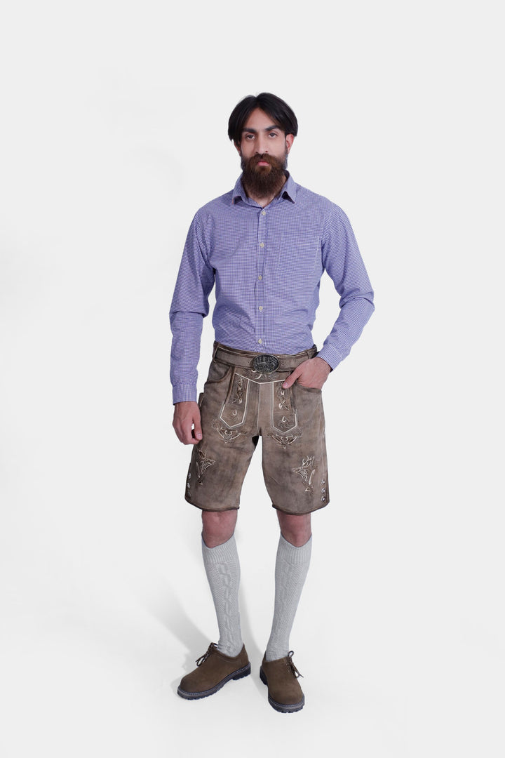 Man in Ski Amadé Lederhosen Outfit with brown leather shorts, blue checkered shirt, and traditional knee-high socks, hands in pockets. trachten lederhosen gürtel , trachten lederhose herren