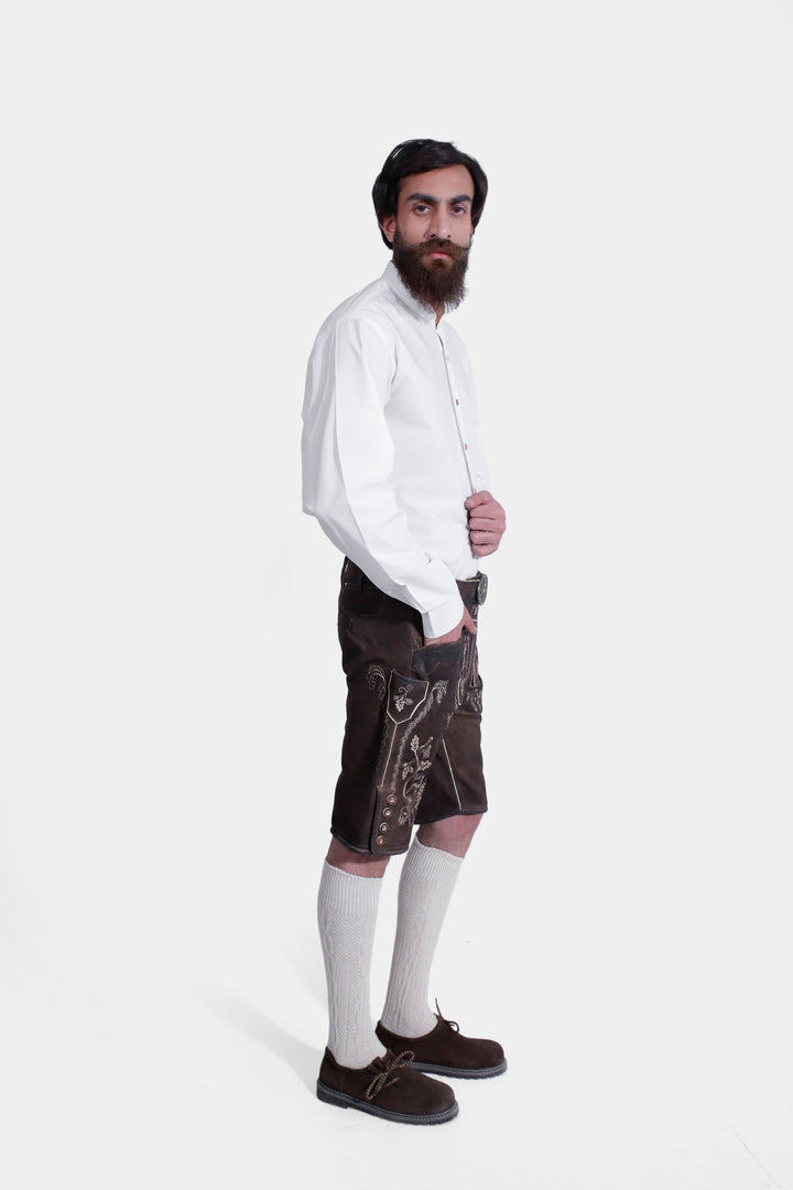 Full-body side view of a model wearing Spiegel Lederhosen, highlighting the side embroidery and buttons on the leather shorts, paired with a white shirt and knee-high socks