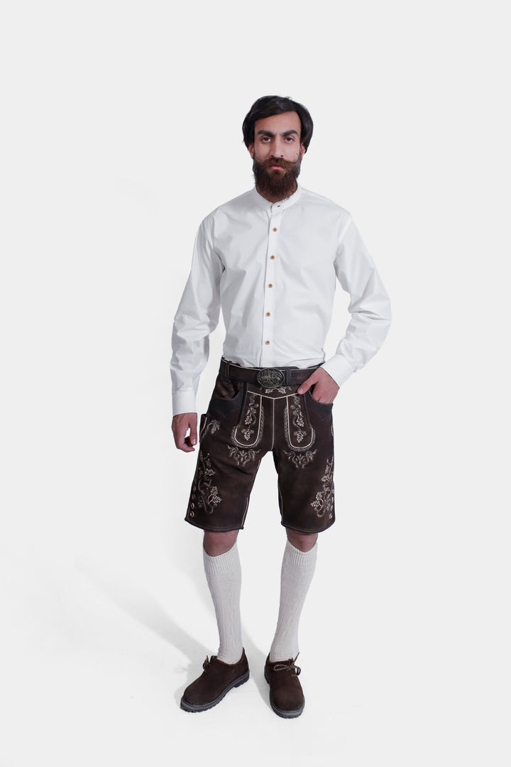 Full-body view of a model wearing Spiegel Lederhosen, a traditional brown leather outfit with intricate embroidery, paired with a white shirt and knee-high socks. lederhose braun herren​, lederhose herren braun​