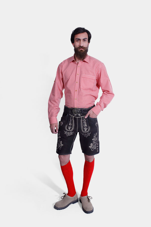 Front view of a man wearing Steuben Lederhosen with a red checkered shirt, showcasing the detailed embroidery and traditional Bavarian style. He is also wearing red socks and beige-colored shoes