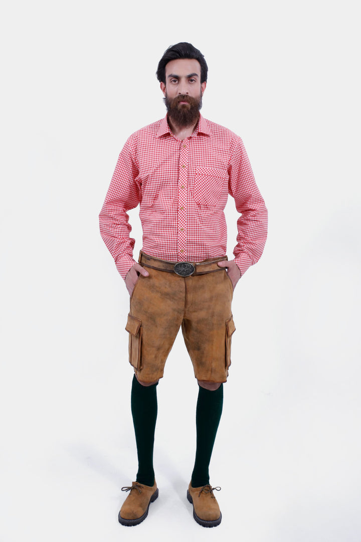 Front view of a man wearing Wagner Cargo Lederhosen with a red checkered shirt, hands in pockets, highlighting the traditional Bavarian style and accessories. lederhose herren tracht kurz