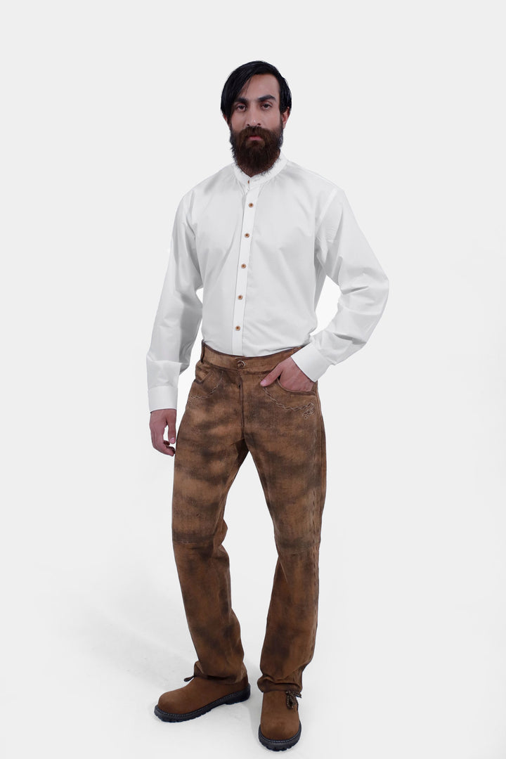 Full-body view of a person standing confidently, dressed in Zugspitze Lederhosen Long Pant with decorative side stitching and a white button-up shirt. lederhose herren lang