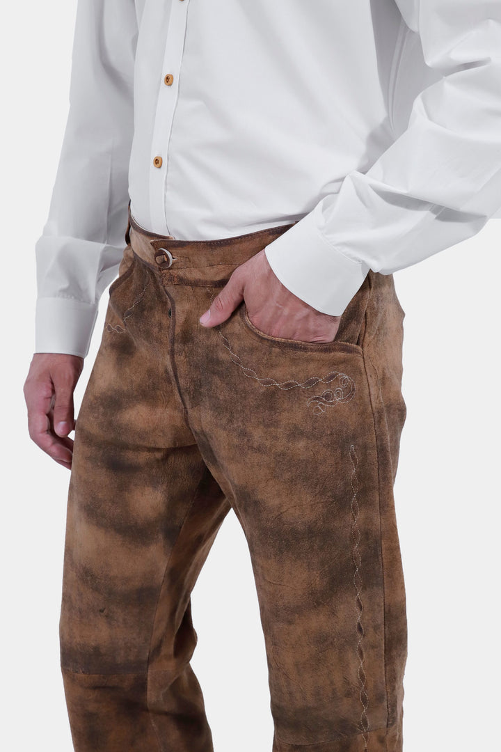 Side view of a person wearing Zugspitze Lederhosen Long Pant, showcasing the intricate embroidery, paired with a white button-up shirt.