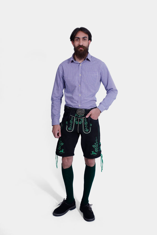 Front view of a man wearing Zwinger Lederhosen in black with green embroidery, paired with a purple gingham shirt and green socks.