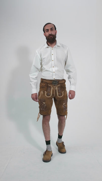 Video showcasing a man modeling traditional Freud Lederhosen, featuring detailed embroidery and classic design. The man rotates to display all angles of the outfit, emphasizing the craftsmanship and fit of the lederhosen, paired with a crisp white shirt. The setting is simple to keep the focus on the attire.