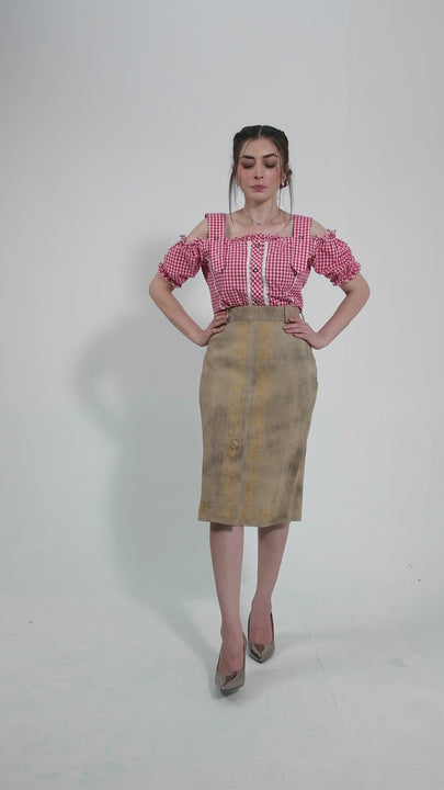 video featuring a model gracefully wearing a traditional beige leather skirt adorned with intricate yellow embroidery, paired with a red and white checkered blouse. The model showcases the skirt from multiple angles, highlighting its elegant design and fine detailing. The video emphasizes the skirt's blend of traditional craftsmanship and modern style, perfect for cultural celebrations and fashionable events.