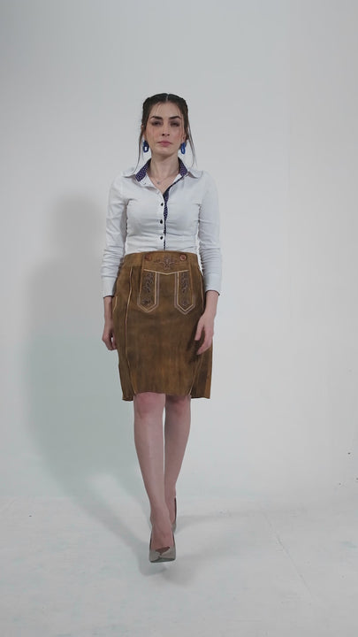 video showcasing a model elegantly dressed in a traditional leather skirt paired with a crisp white blouse. The model strikes various poses, highlighting the skirt's detailed embroidery and unique craftsmanship. The video emphasizes the skirt's blend of cultural heritage and contemporary style, making it an ideal choice for festive occasions and stylish outings.