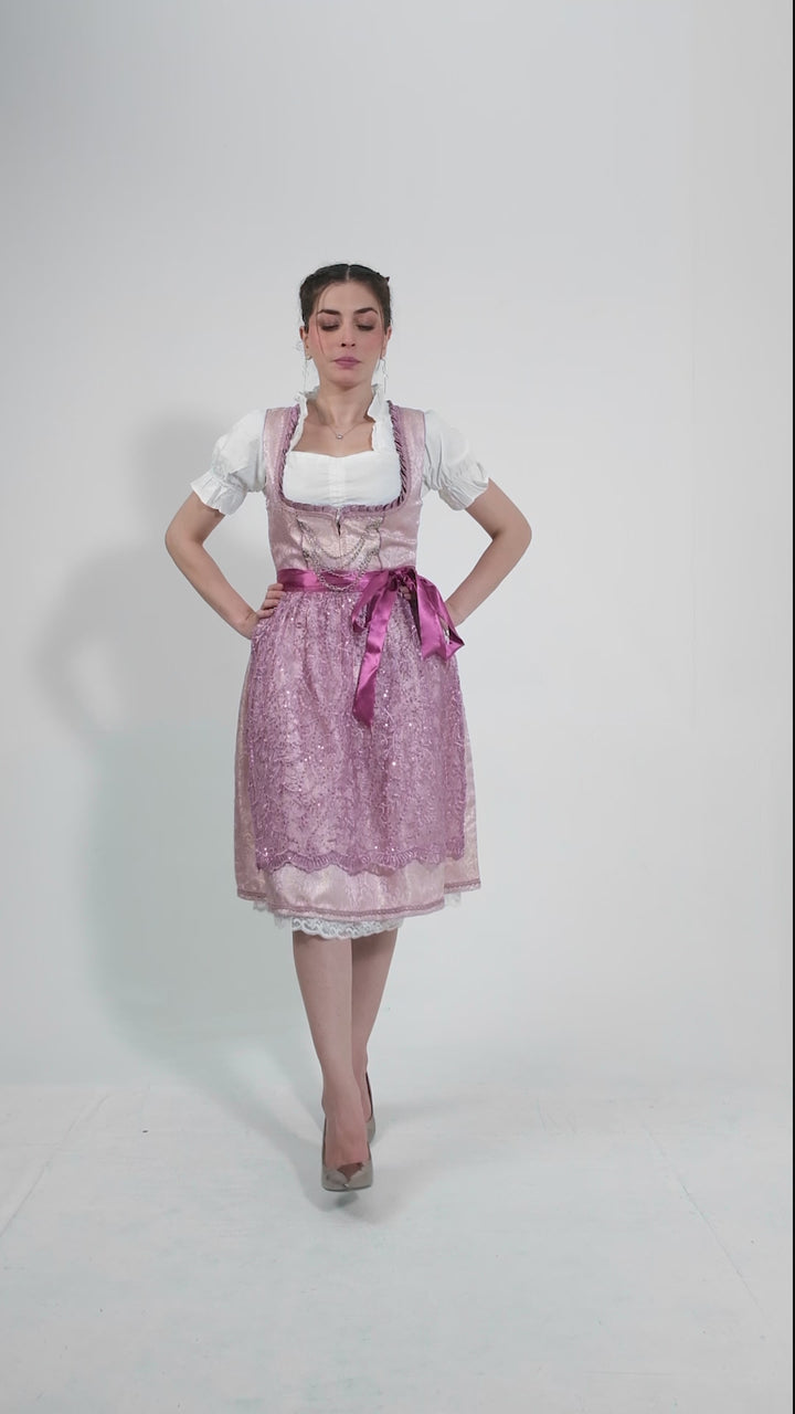 Video showcasing a model twirling in the Dirndl Jessica Schwarz, highlighting the intricate lace details on the apron and the sparkling embellishments on the bodice, set against a plain background to emphasize the outfit's elegance.