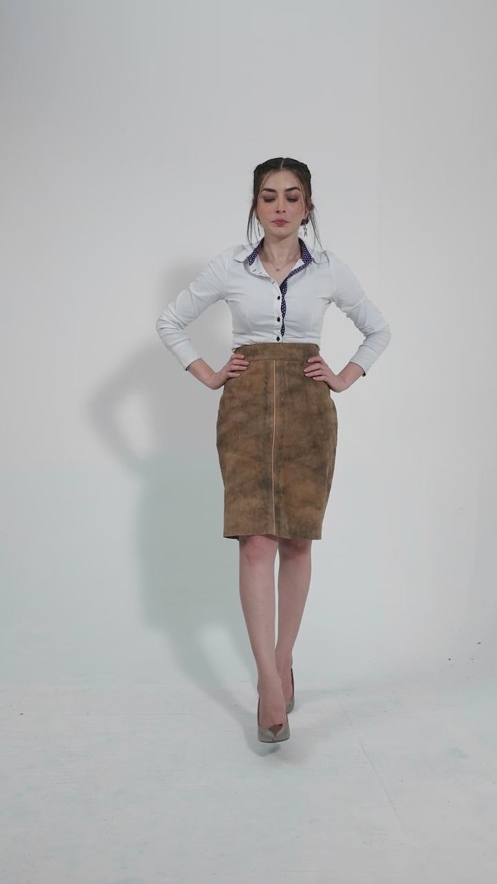 video featuring a model showcasing a traditional leather skirt paired with a stylish white blouse. The model presents the skirt from different angles, emphasizing the fine stitching and the rich texture of the leather. The video captures the elegance and cultural authenticity of the IRINA Lederhosen Skirt, making it a perfect choice for both festive occasions and casual outings.